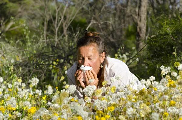 Woman suffering hay fever in field of wildflower — Stock Photo, Image