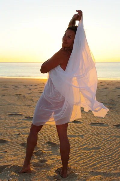 性感的女人白色布在日落海滩跳舞 — 图库照片
