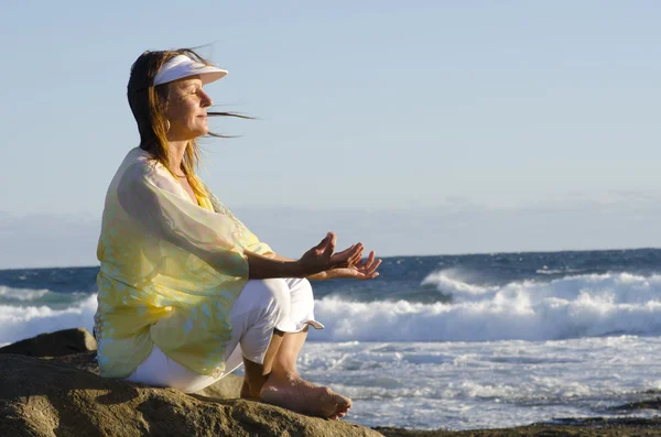 Уверенная сексуальная женщина медитирует изолированно на вершине скалы у океана — стоковое фото