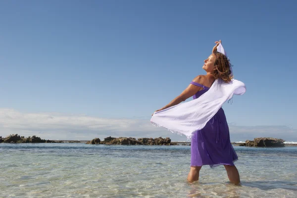 Сексуальная женщина в фиолетовом платье счастлива на пляжном отдыхе — стоковое фото