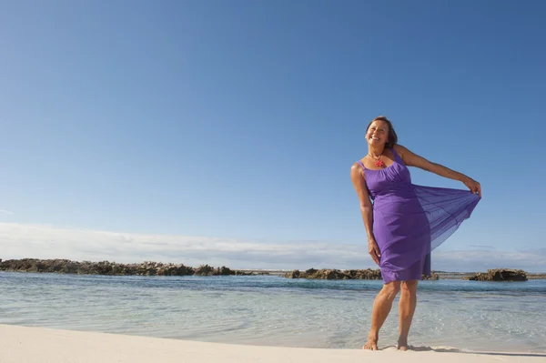 Sexy vrouw in paarse jurk gelukkig op strand — Stockfoto