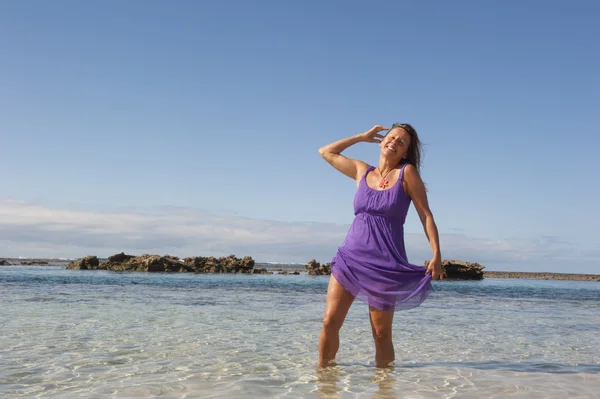 Sexy kobieta w fioletowy strój szczęśliwy na plaży — Zdjęcie stockowe
