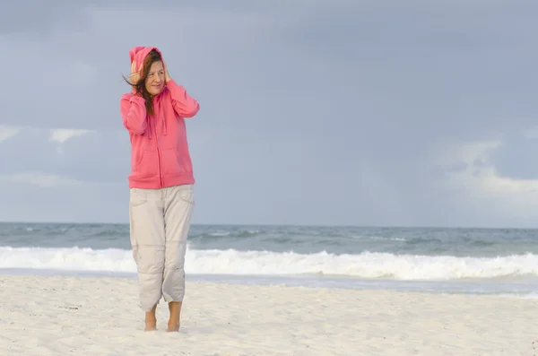 Зрелая женщина расслабилась в ветреный холодный день у океана — стоковое фото