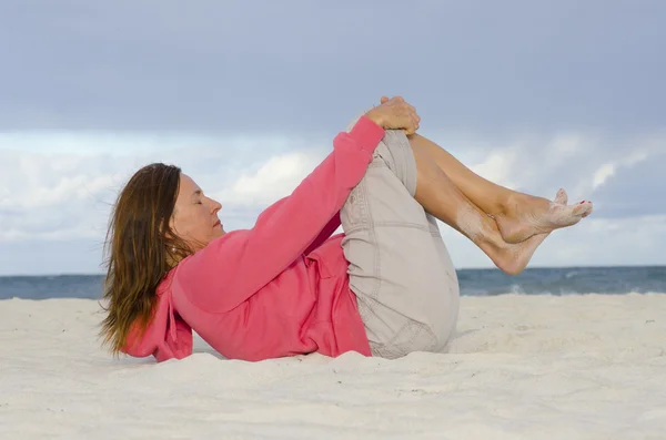 Aantrekkelijke volwassen vrouw uitoefenen op strand — Stockfoto