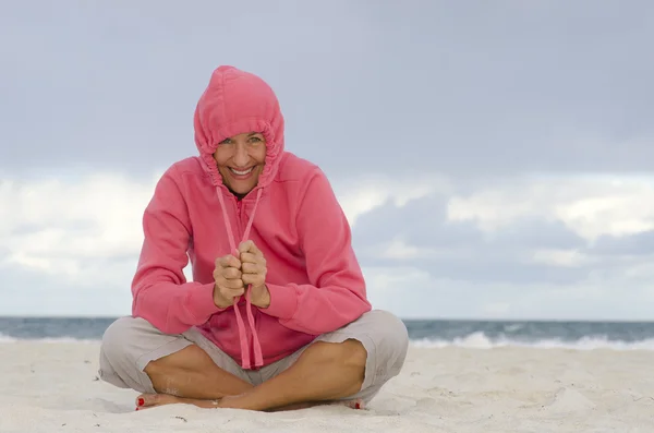 Mogen kvinna vackra leende blåsig kall dag på stranden — Stockfoto