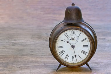 Antique clock on a wooden background clipart