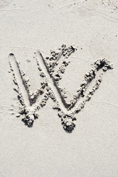 The letter W of the alphabet writing on the sand beach