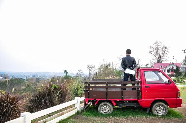 Hombre de pie en un pequeño vehículo rojo de recogida —  Fotos de Stock
