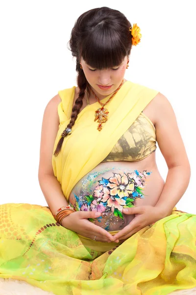 The pregnant girl with the drawn picture on a stomach in a yello — Stock Photo, Image