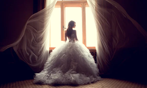 A bela noiva contra uma janela em casa — Fotografia de Stock