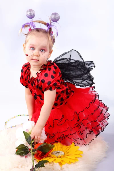 Het kleine meisje in een pak lieveheersbeestjes met kleuren op een witte backg — Stockfoto