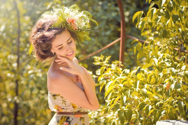 Ένα όμορφο κορίτσι σε ένα ελαφρύ φόρεμα με λουλούδια στο πάρκο — Φωτογραφία Αρχείου
