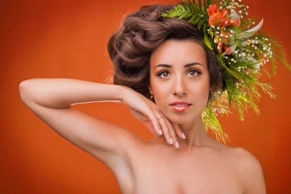 Красива дівчина з квітами на голові на помаранчевому фоні — стокове фото