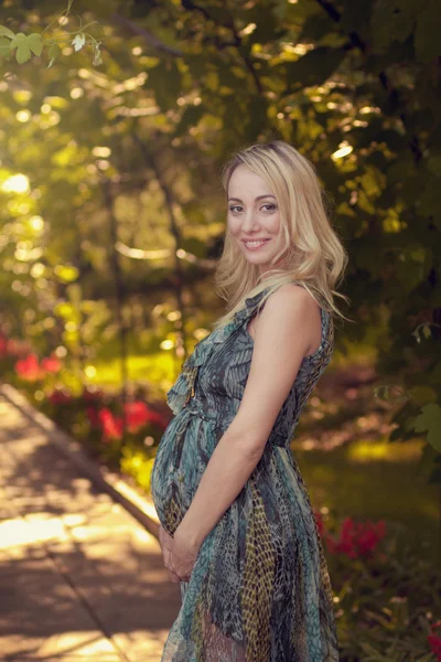 Een mooie zwangere meisje in het park in de schemering, 's avonds — Stockfoto