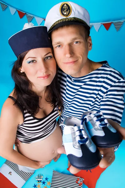 Couple in love during pregnancy in a marine style, with cushions — Stock Photo, Image