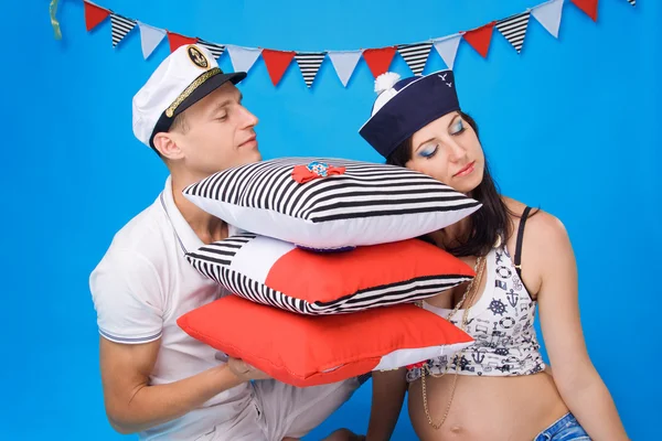 Couple in love during pregnancy in a marine style, with cushions — Stock Photo, Image