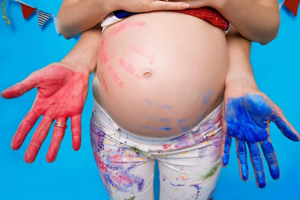 Uma barriga grávida com um azul e vermelho impressões das palmas das mãos em uma ma — Fotografia de Stock