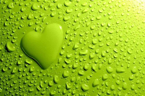 Капли воды и форма сердца на зеленом фоне — стоковое фото