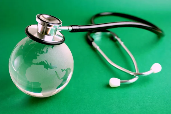 Stethoscope and crystal globe - green background — Stock Photo, Image