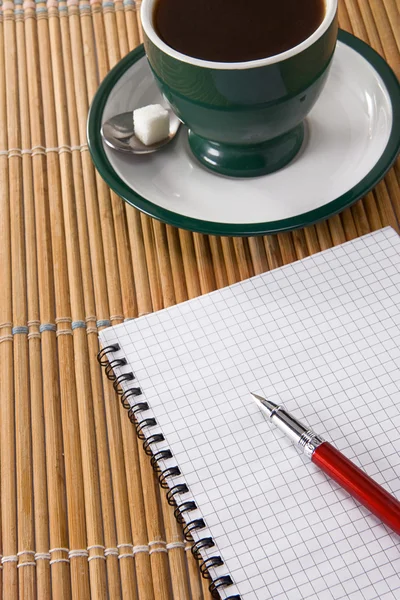 Taza de café y pluma de tinta con cuaderno a cuadros —  Fotos de Stock