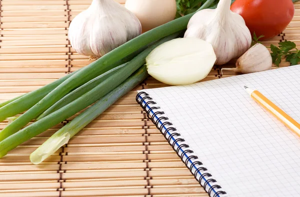 Quaderno con matita, aglio, pomodoro e cipolla — Foto Stock
