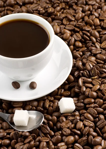 Tasse voller Kaffee und Bohnen — Stockfoto