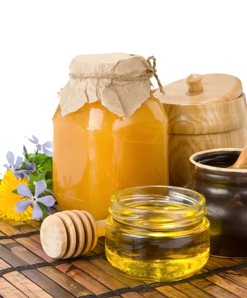 Honey, flowers and jars on white — Stock Photo, Image
