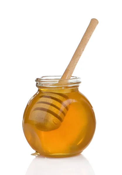 Glass pot full of honey and stick isolated on white — Stock Photo, Image