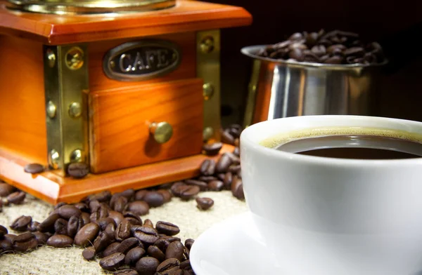 Tasse Kaffee, Bohnen, Topf und Mühle auf Säcke — Stockfoto