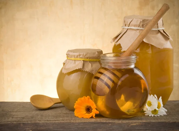 stock image Jar of honey and flowers on wood