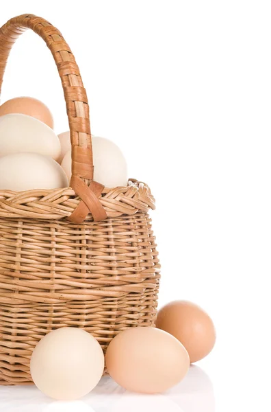 Яйца и корзина на белом фоне — стоковое фото