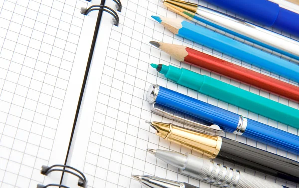 Ручка и карандаш на ноутбуке — стоковое фото
