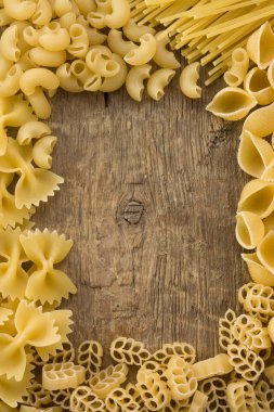 Raw pasta on wood background clipart