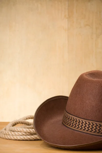 Brown cowboy hat and rope on wood — Stock Photo, Image