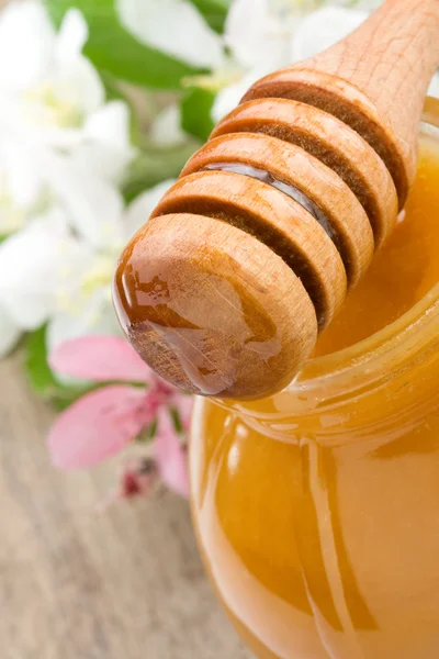 Honey in glass and stick with flowerson wood — Stock Photo, Image