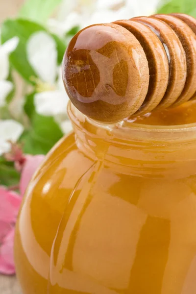 Honig im Glas und Stick mit Blüte — Stockfoto