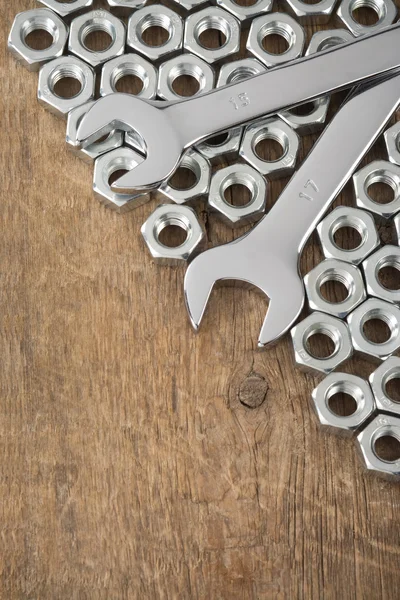 Metalen moeren en moersleutel tool op hout achtergrond — Stockfoto