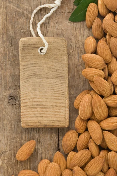 Nueces almendra y precio de etiqueta en madera —  Fotos de Stock