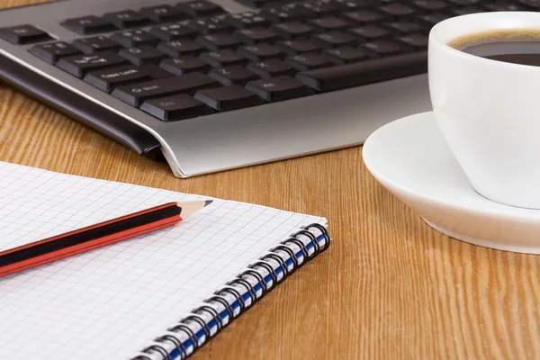 Teclado, caderno e xícara de café na mesa — Fotografia de Stock