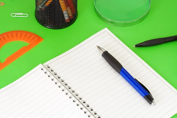 Pennen, potloden, Vergrootglas en pad op groen — Stockfoto