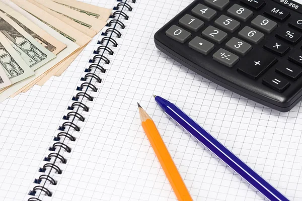 Калькулятор, ручки и доллары на площадке — стоковое фото
