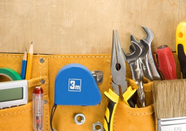 Tools in construction belt on wooden background