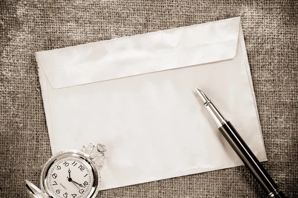 Zarf vintage çuval arka plan üzerinde saat ve mürekkep kalem — Stok fotoğraf