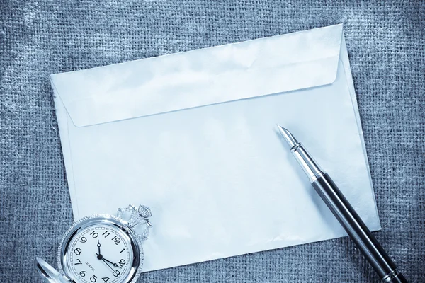 Часы и чернила ручка на конверте на винтажном фоне мешок — стоковое фото