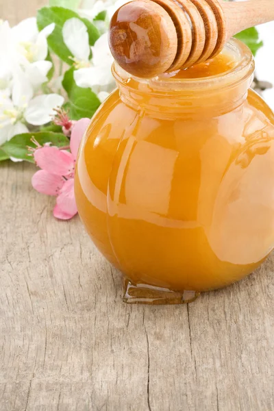 Miel dans un bocal en verre et bâton de fleurs — Photo