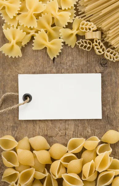 Ruwe pasta en prijskaartje label op hout — Stockfoto