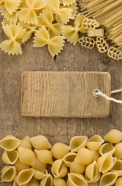 Ruwe pasta en prijskaartje label op hout — Stockfoto
