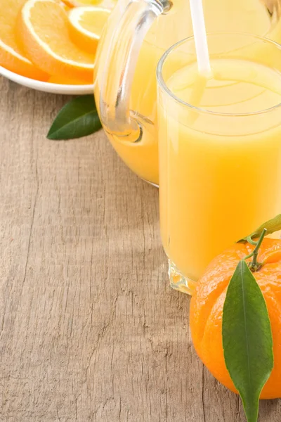 Vers fruit sap in glas en oranje op hout — Stockfoto