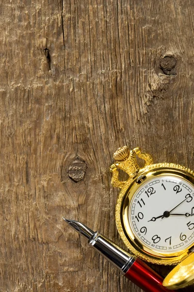 Чернильное перо и часы на дереве — стоковое фото