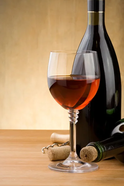 Glass of red wine and bottle with grape on wood — Stock Photo, Image